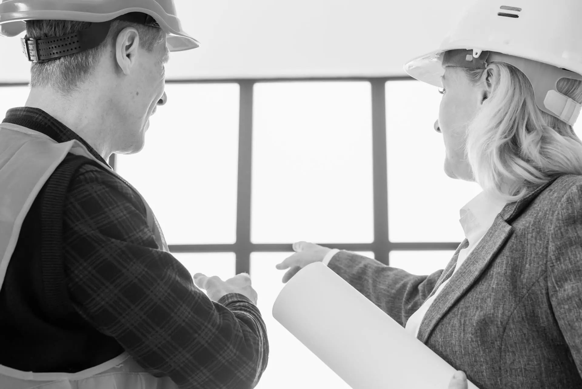 Two engineers in hard hats reviewing plans on site