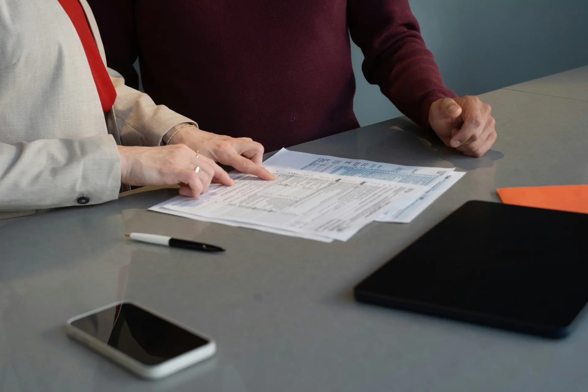 Two people reviewing a printed engineering compliance report across a meeting table