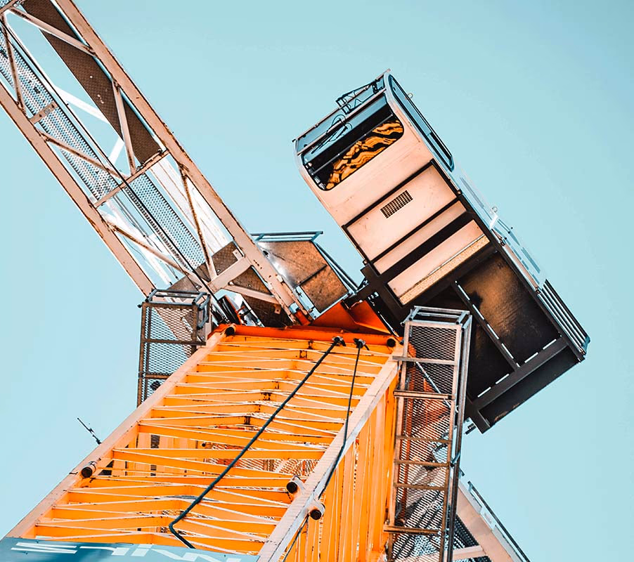 Orange tower crane jib and operator cab viewed from below