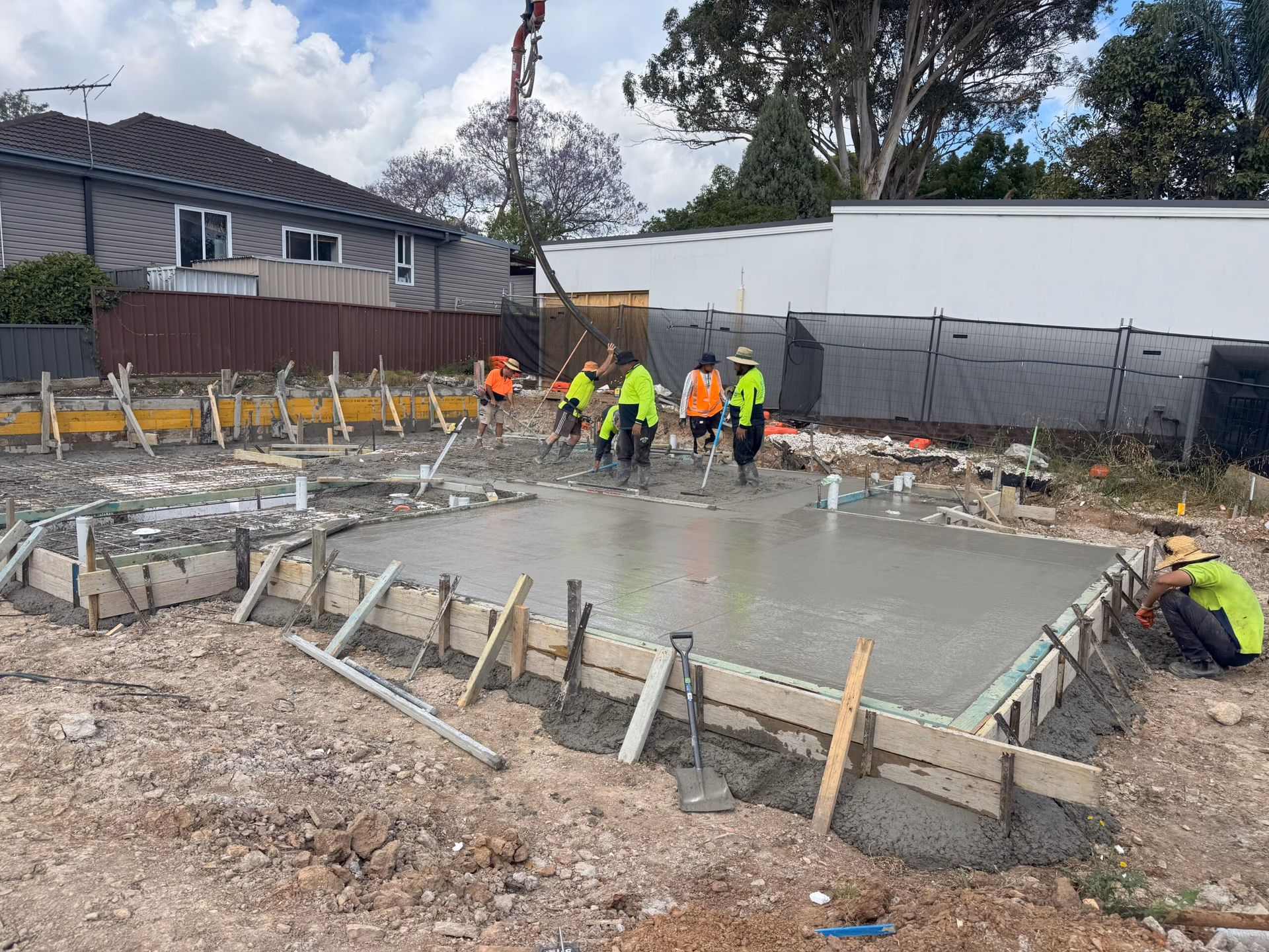Concrete slab pour with pump boom and workers finishing