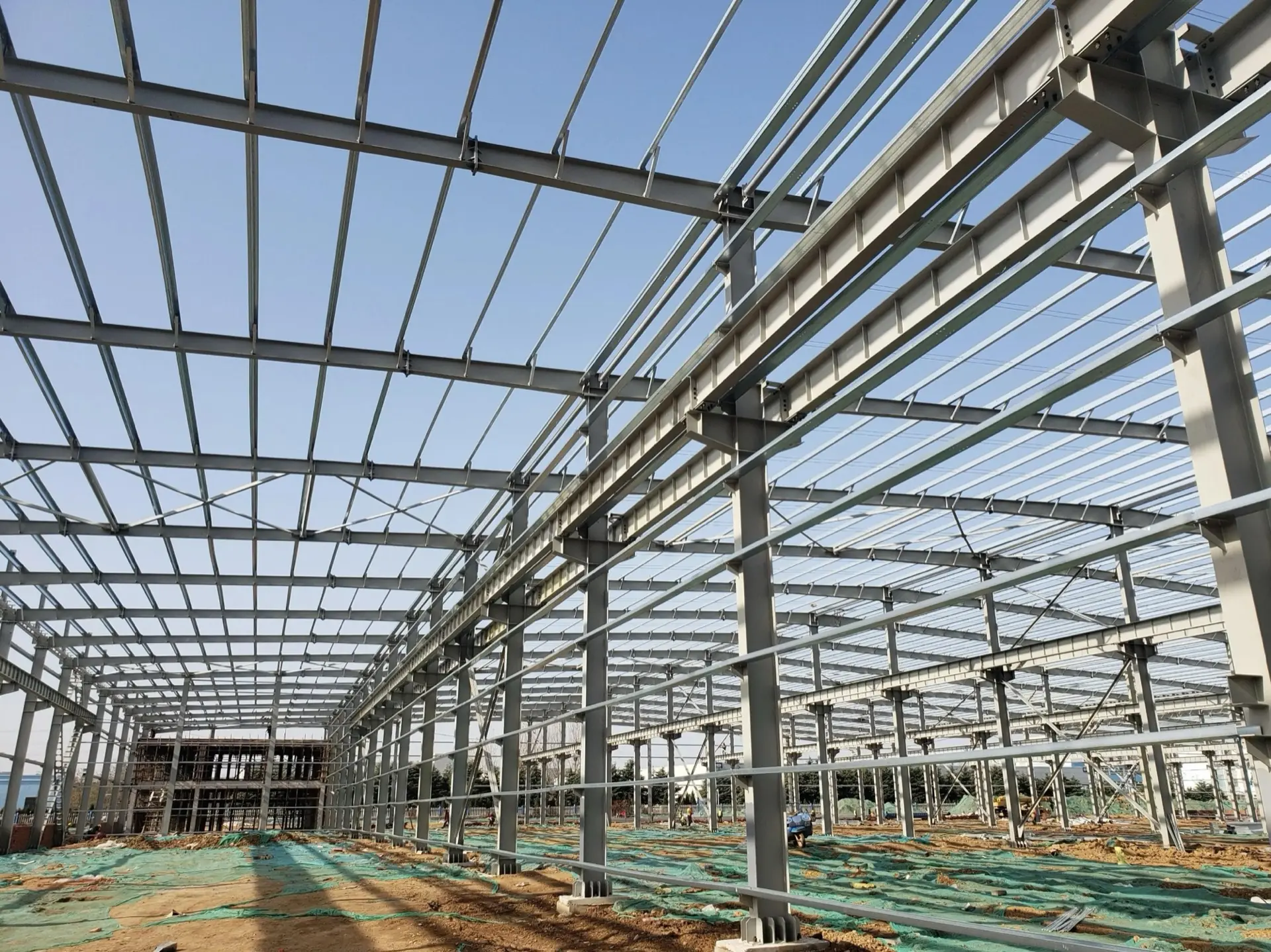 Steel portal frame warehouse under construction, seen along the rafters and roof purlins