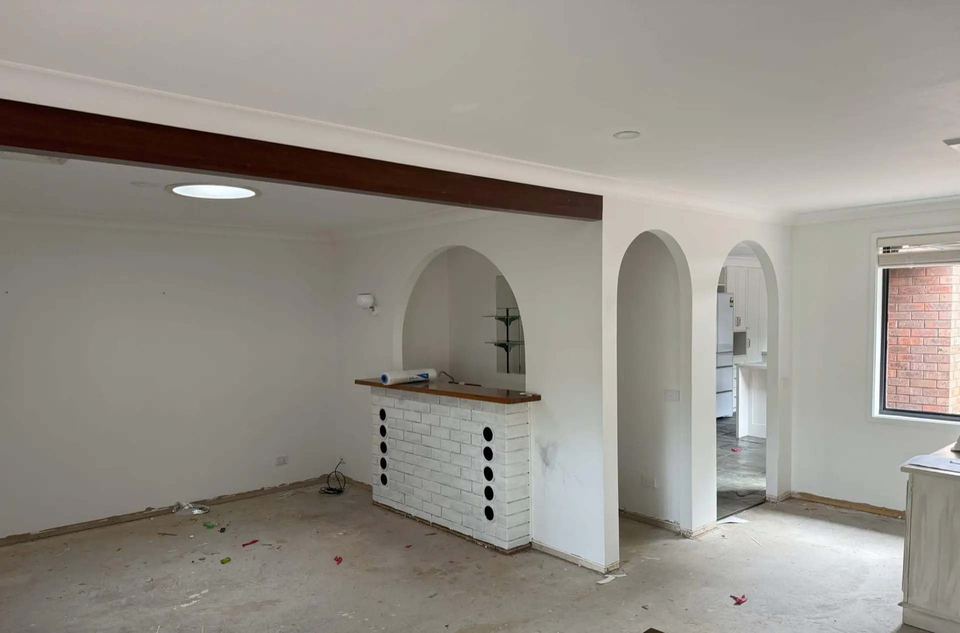 Living area before the renovation — archways and a brick servery under a timber beam dividing the space into separate rooms