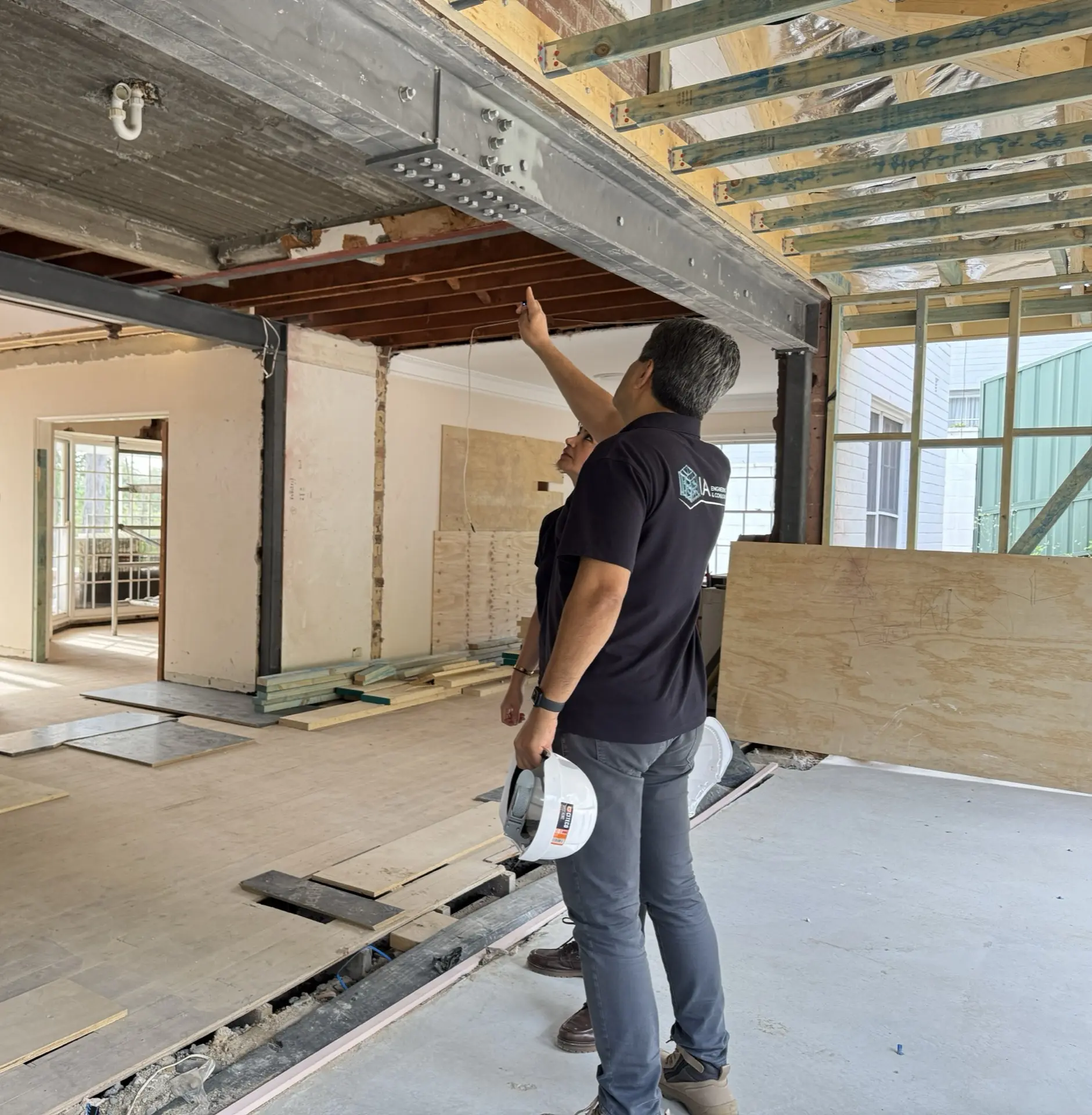 IA Engineering staff inspecting a newly installed steel transfer beam in a stripped-back house